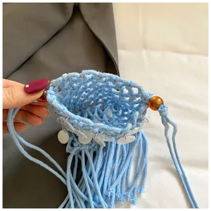 Close-up of light blue crochet phone bag with white sequin charms and fringe detail