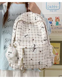 Detailed view of the cute cartoon bear pattern and plush pendant on plaid backpack