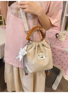 Dettaglio di una graziosa borsa a secchiello color crema con ciondolo a stella e manico imbottito.
