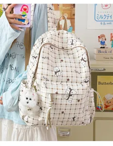 Close-up detail of a cute beige checkered student backpack with bear patterns and plush charm