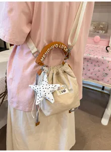 Primo piano di una borsa a secchiello beige con ciondolo a stella e manico marrone