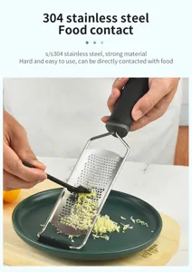 Detail shot of stainless steel cheese grater shredding food on plate, kitchen tool.
