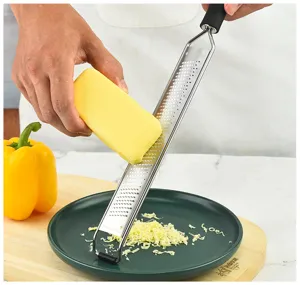 Edelstahl Käsereibe Detailaufnahme beim feinen Reiben von Käse auf dem Schneidebrett.