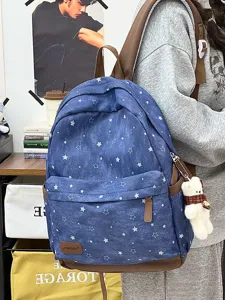 Detailansicht eines blauen Schülerrucksacks mit Sternmuster und süßem Bärenanhänger.