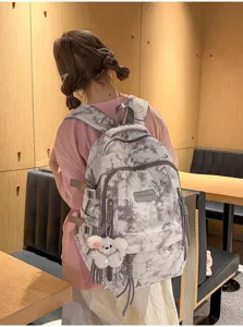 Grey tie-dye high-capacity school backpack with cute plush bear pendant shown on model