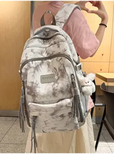 Detailed back view of a stylish tie-dye schoolbag featuring a cute plush rabbit charm