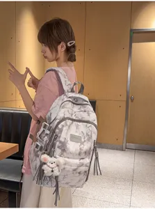Asian student model wearing a large capacity tie-dye school backpack in casual setting