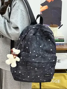 Nahaufnahme eines Vintage-Rucksacks mit Sternmuster, Plüschbär-Anhänger und Markenlogo