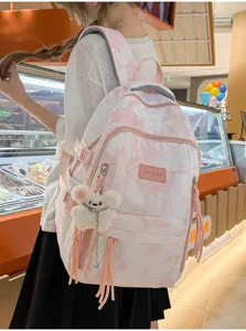 Large capacity tie-dye school backpack with cute bear charm shown worn by a student in a cafe