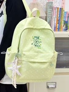 Detail eines hellgrünen Rucksacks mit Sternmuster, Kleeblatt-Stickerei und Anhänger