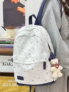 Ein Student trägt einen Vintage-Rucksack mit Sternenmuster und süßem Plüschbären-Anhänger.