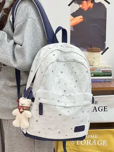 Detailansicht eines weißen Schulrucksacks mit grauen Sternmustern und einem süßen Bären-Plüschtier