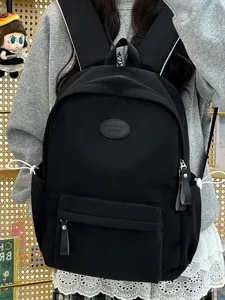 Detailansicht eines schwarzen minimalistischen Schulrucksacks mit ovalem Logo-Patch