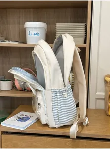 Dettaglio della vista laterale di uno zaino scolastico crema con strisce blu eleganti