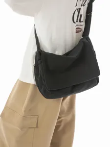 Schwarze Canvas-Umhängetasche im Vintage-Stil mit Klappe, am Rücken des Modells getragen