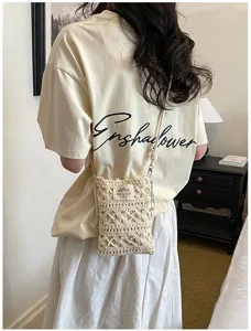 Close-up view of a minimalist handmade cream crochet phone crossbody bag worn by a model