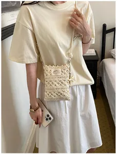 Detail view of a handmade cream crochet phone bag with hollowed-out knit pattern