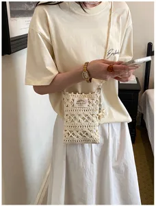 Handmade ivory crochet cell phone bag with elegant hollow knitted pattern shown on model
