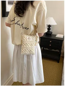 Detailed view of cream handmade crochet crossbody phone bag in a warm lifestyle setting