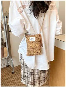 Back view of a woman wearing a hand-knitted hollow straw-style crossbody phone bag