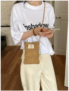 Close-up of handmade crochet crossbody phone bag worn with casual white t-shirt