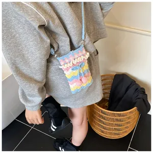 Detailansicht einer handgefertigten, bunten Häkel-Handytasche mit Kirsch- und Schleifendekor