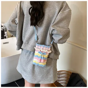 Detailaufnahme einer handgestrickten Umhängetasche mit bunten Kirsch- und Schleifenakzenten.