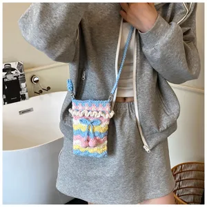 Handgefertigte gestrickte bunte Kirsch-Handytasche in einer Lifestyle-Umgebung
