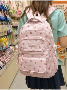 A stylish pink student backpack with cute red star patterns shown being worn by a girl.