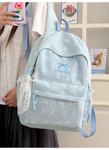 Vue détaillée d'un sac à dos d'écolier à carreaux bleus avec de jolis nœuds brodés
