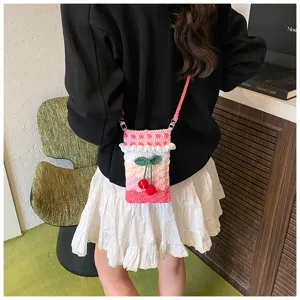 Charmante handgefertigte Häkel-Handytasche mit Kirschdesign über einem weißen Rock