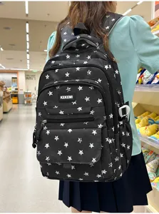 Back view of a black school backpack with white star patterns worn by a student
