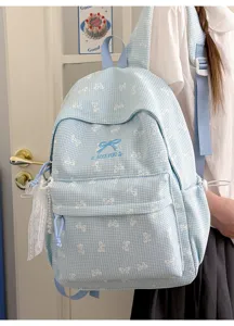 Détail d'un sac à dos vichy bleu clair avec des motifs de rubans blancs et un charme en dentelle
