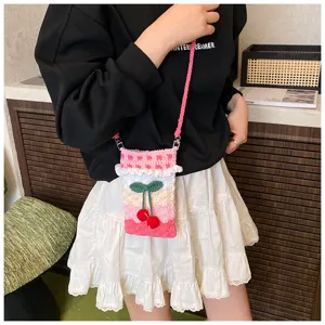 Detailansicht einer handgestrickten rosa Kirsch-Umhängetasche, getragen von einem Modell
