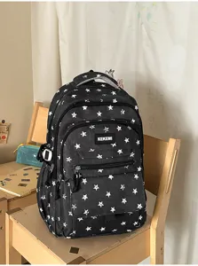 Large capacity black backpack with white star patterns for students shown on a chair
