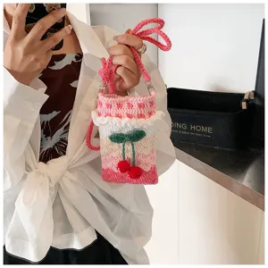 Handgefertigte Häkel-Handytasche mit süßem Kirschanhänger in einer Lifestyle-Umgebung