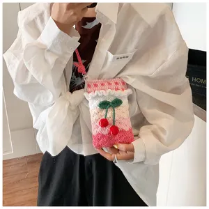 Detailaufnahme einer handgefertigten Häkel-Handytasche mit Kirsch-Akzenten am Modell