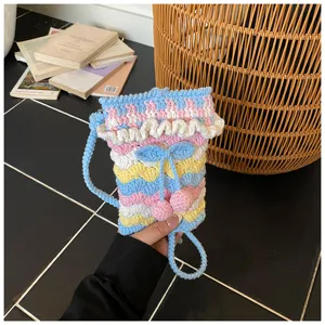 Detailansicht der handgestrickten Kirschtasche mit bunten Rüschen und blauem Tragegurt