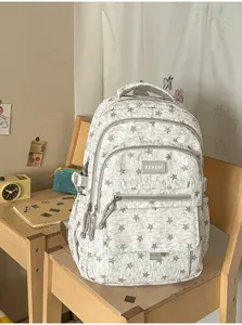 Detail view of a stylish grey star pattern student backpack resting on a wooden chair.