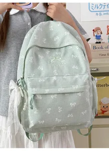 Détail d'un sac à dos vichy vert avec un joli nœud en dentelle et une perle