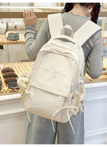 Vue arrière d'un sac à dos blanc crème pour étudiant avec broderie 'Have a good day' chic.