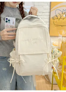 Détail d'un sac à dos blanc crème avec broderie Have a good day et nœuds décoratifs