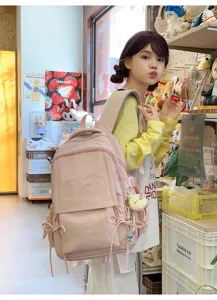 Vue détaillée d'un sac à dos d'écolier rose avec broderie 'Have a good day' et nœud.
