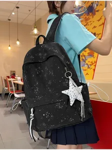 Vista trasera de estudiante con mochila negra con estampado de estrellas y llavero
