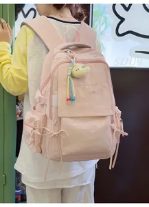 Sac à dos rose clair avec broderie et breloque mignonne, porté par un mannequin de dos.