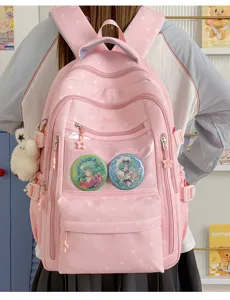 Vue arrière d'un sac à dos d'école rose avec motif d'étoiles et badges d'anime