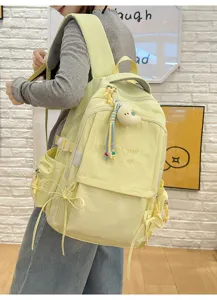 Vue détaillée du sac à dos jaune avec broderie 'Have a good day' et accessoires.