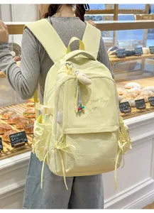 Détail d'un sac à dos jaune avec broderie porté par un mannequin dans un décor de boulangerie