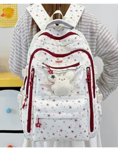 Vue détaillée d'un sac à dos d'école blanc avec des motifs d'étoiles rouges et lapin