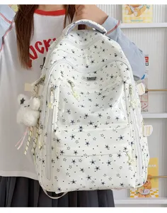 Vue détaillée d'un sac à dos d'école blanc avec motifs d'étoiles et pendentif en peluche